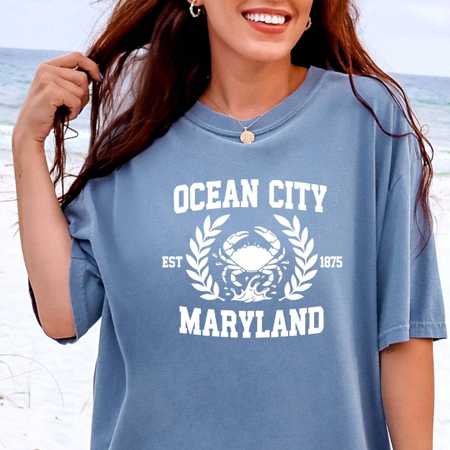 Person wearing a blue t-shirt with 'Ocean City, Maryland' printed on it at the beach.