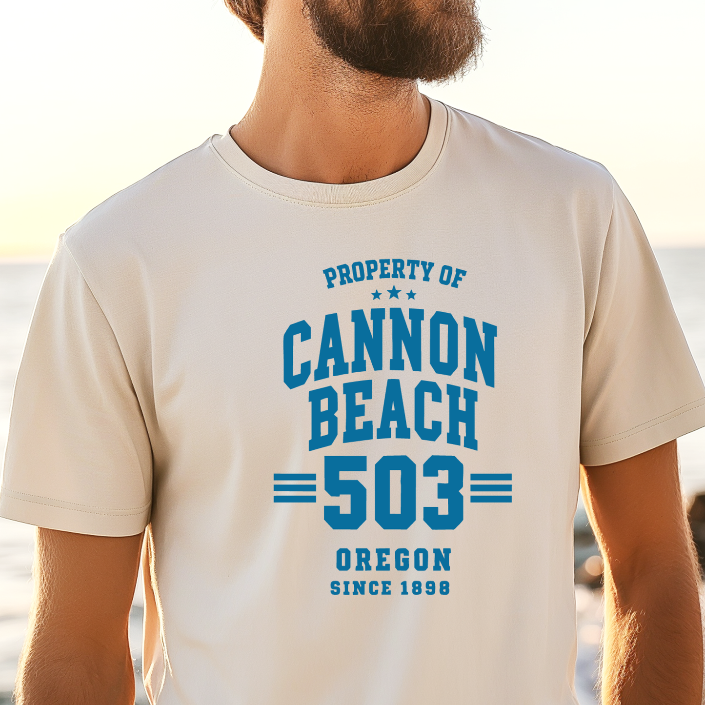 Person wearing a t-shirt with 'Property of Cannon Beach 503 Oregon Since 1899' text at the beach.