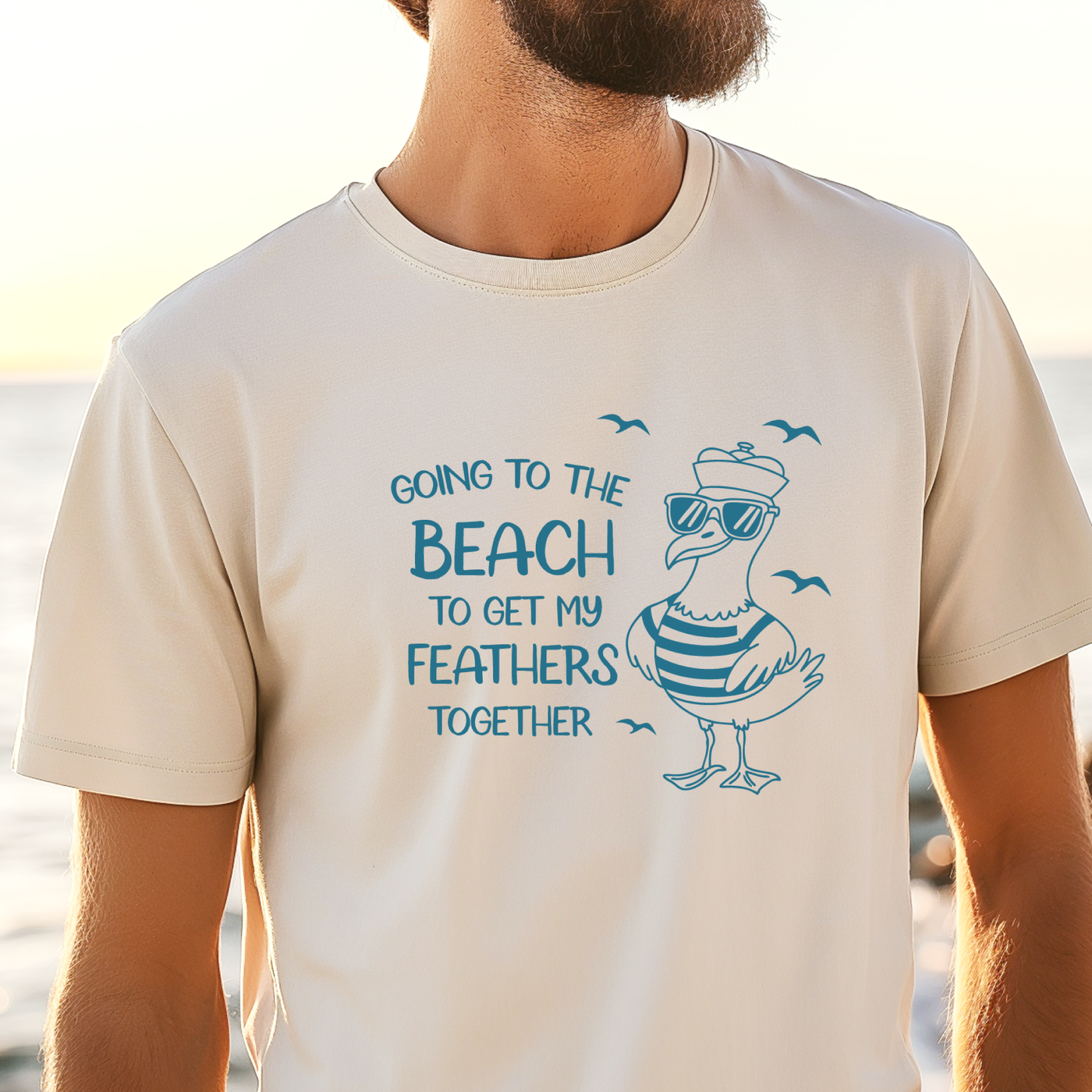 Comfort Colors t-shirt featuring a humorous blue seagull graphic wearing sunglasses and a striped shirt, beside the text “Going to the Beach to Get My Feathers Together.” Several flying birds surround the design, adding a fun coastal feel. This unisex garment-dyed tee offers a soft, vintage texture and relaxed fit, perfect for beach lovers, ocean fans, and anyone who enjoys playful summer graphic shirts.