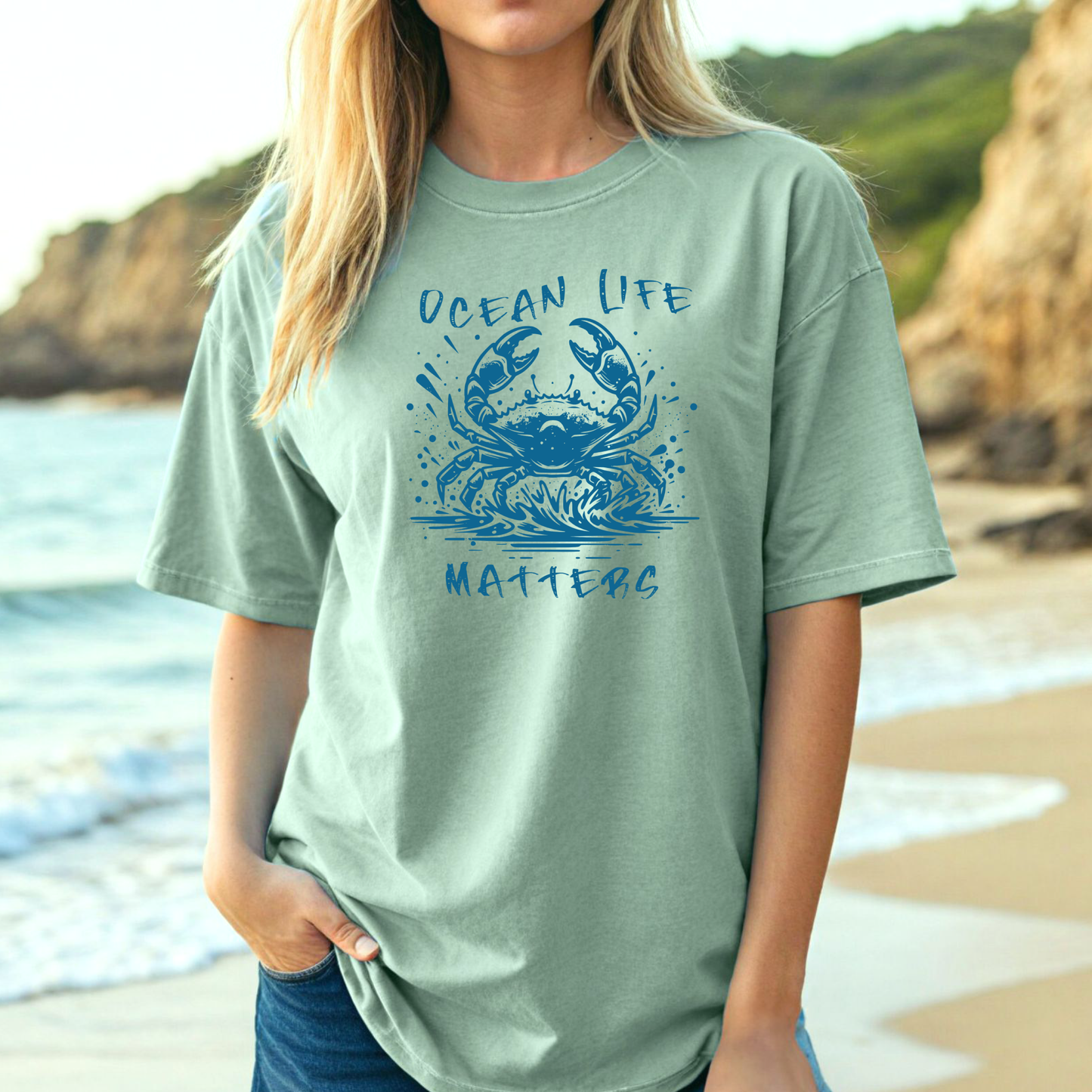 Comfort Colors 1717 "Ocean Life Matters" t shirt with a crab splashing in water in a one color graphic. Picture of a girl standing on the beach wearing an oversized t shirt.