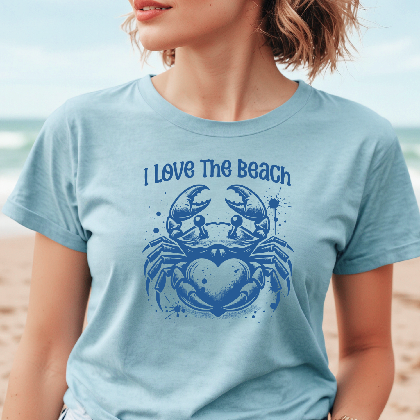 Bella Canvas 3001 "I Love The Beach" t shirt with a crab holding a heart one color graphic. Picture of a girl standing on the beach wearing a t shirt.
