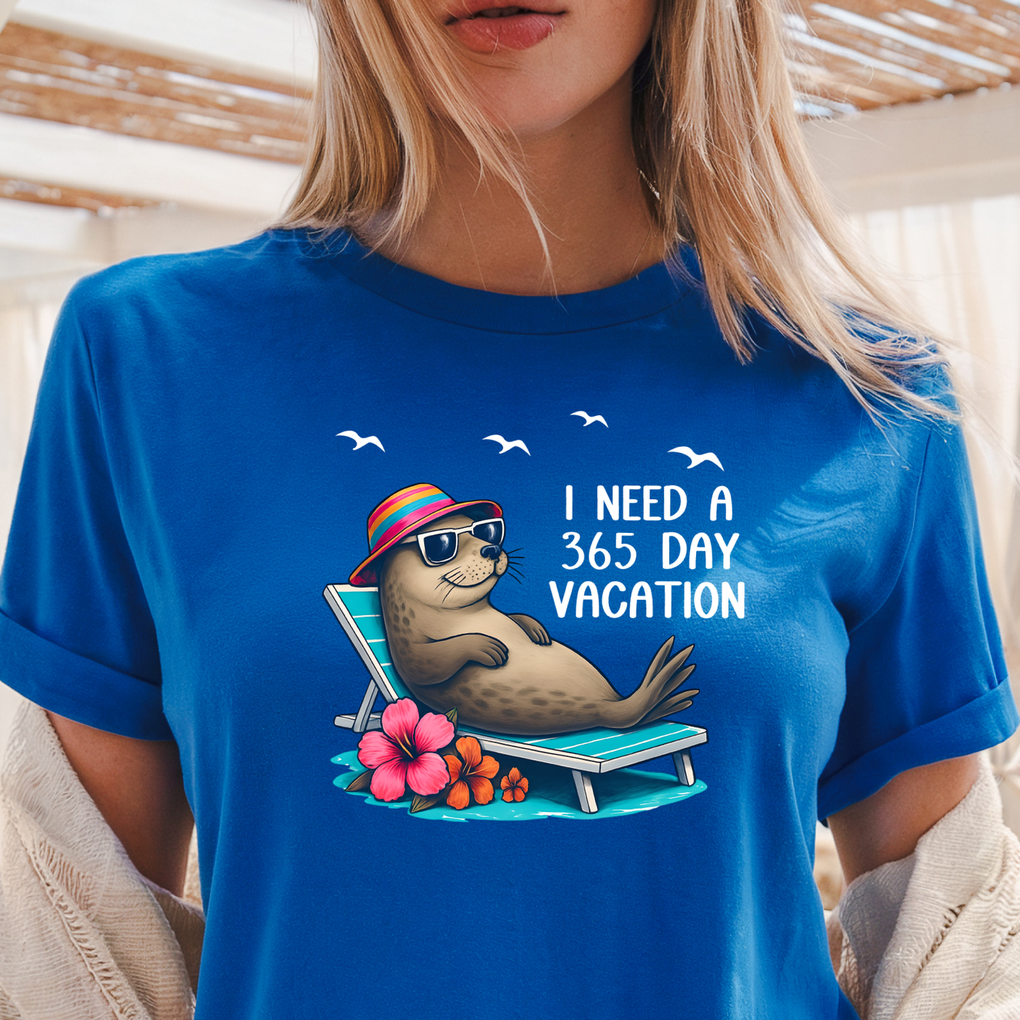 Person wearing a Royal blue t-shirt with a seal graphic and text 'I Need a 365 Day Vacation'.