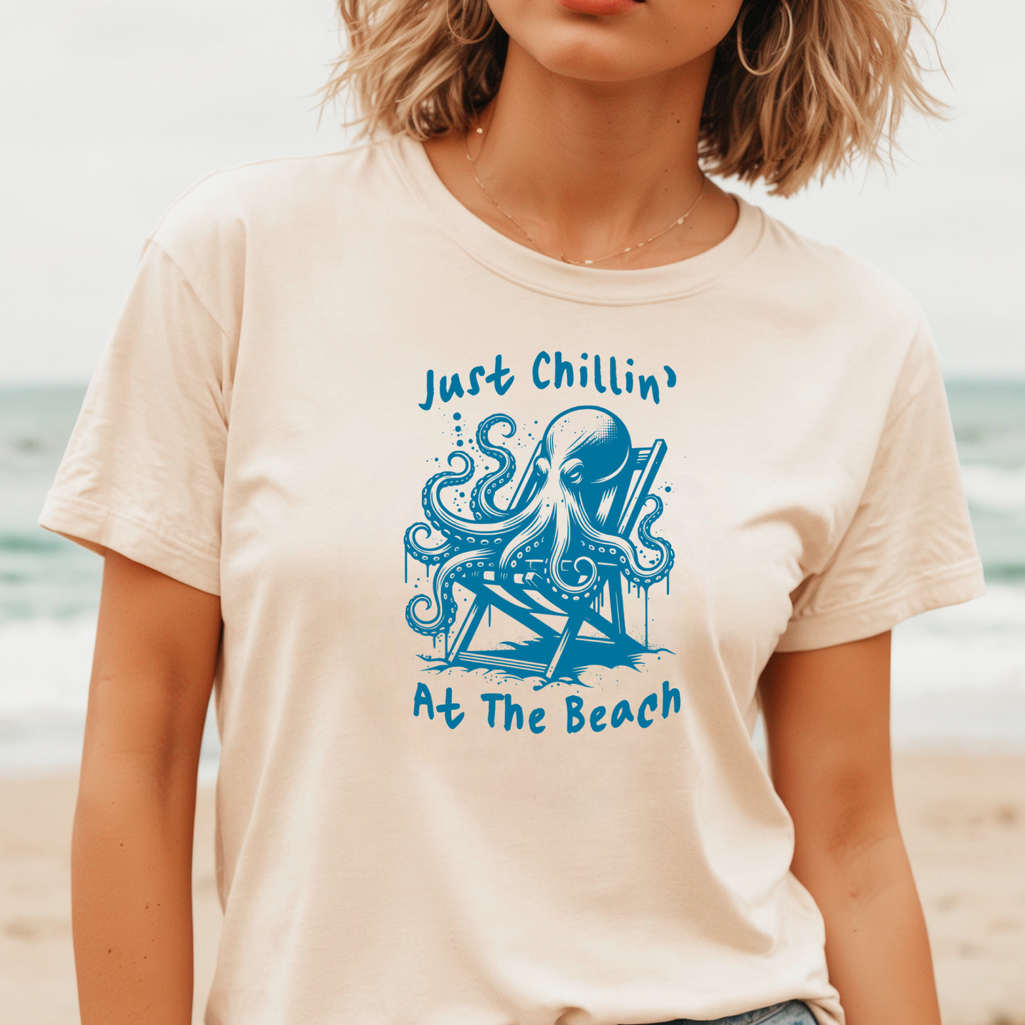 Gildan 5000 "Just Chillin' At The Beach" t shirt with an octopus setting in a beach chair in one color graphics. Picture of a girl standing on the beach wearing a t shirt.