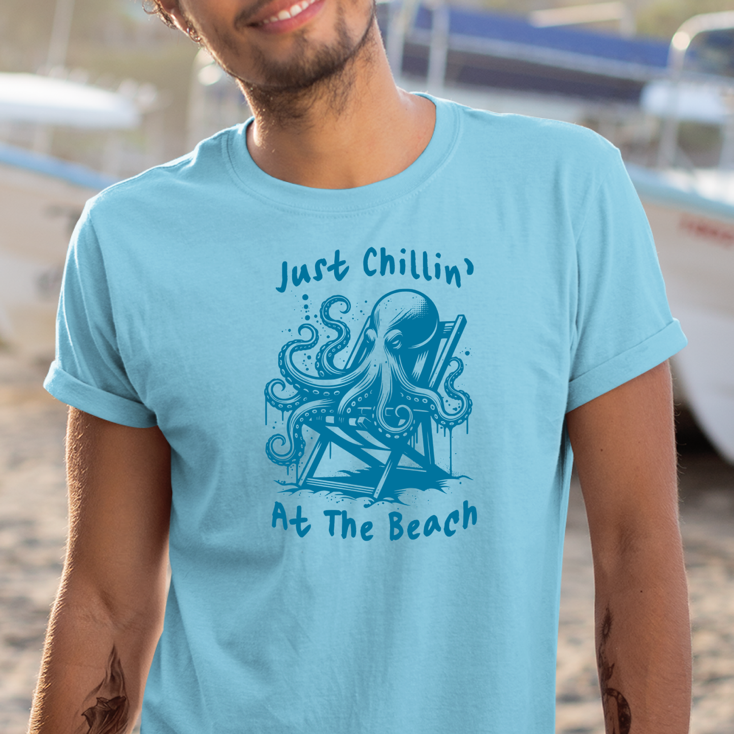 Gildan 5000 "Just Chillin' At The Beach" t shirt with an octopus setting in a beach chair in one color graphics. Picture of a man standing in a boat yard wearing a t shirt.