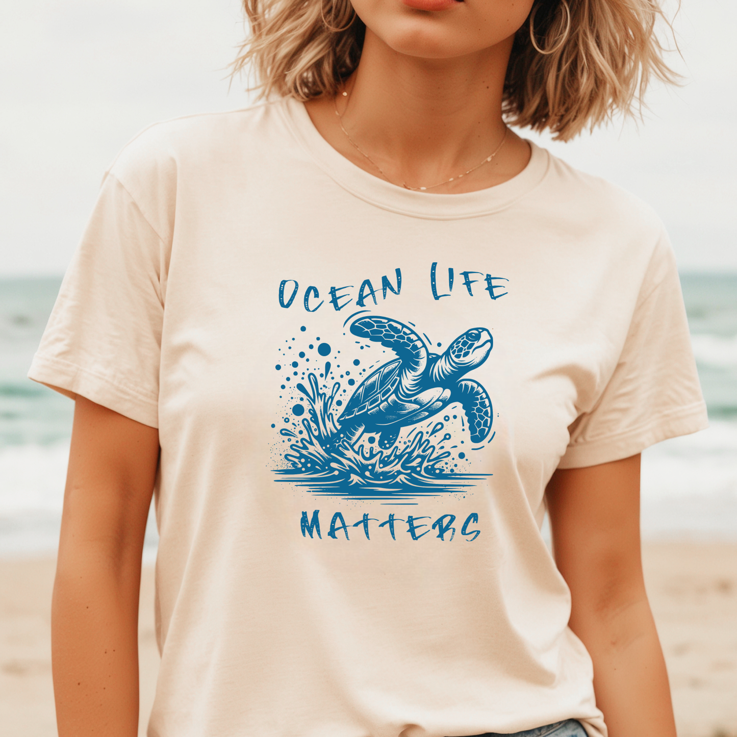 Gildan 5000 "Save The Ocean and The Sea Life In It" t shirt with a sea turtle splashing in water in a one color graphic. Picture of a girl standing on the beach wearing a t shirt.