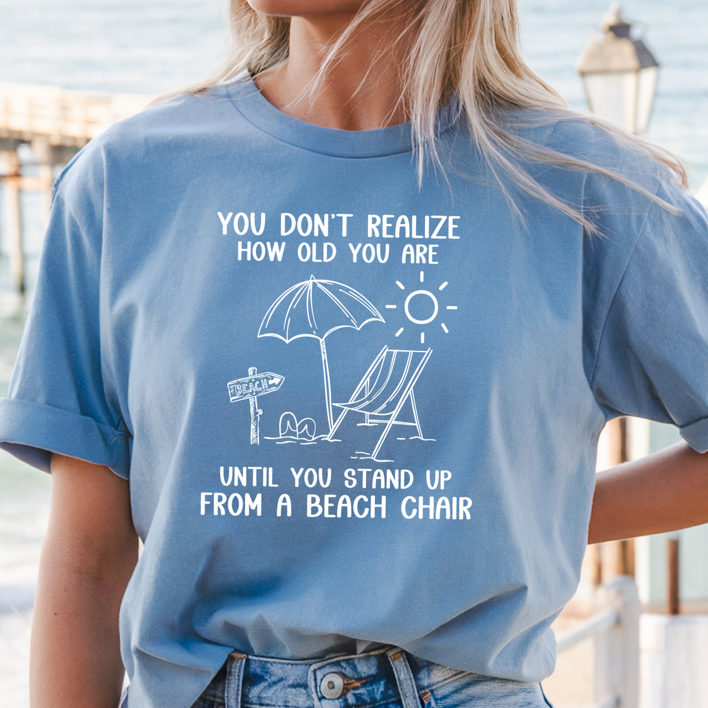 Person wearing a blue t-shirt with a beach-themed graphic and text.