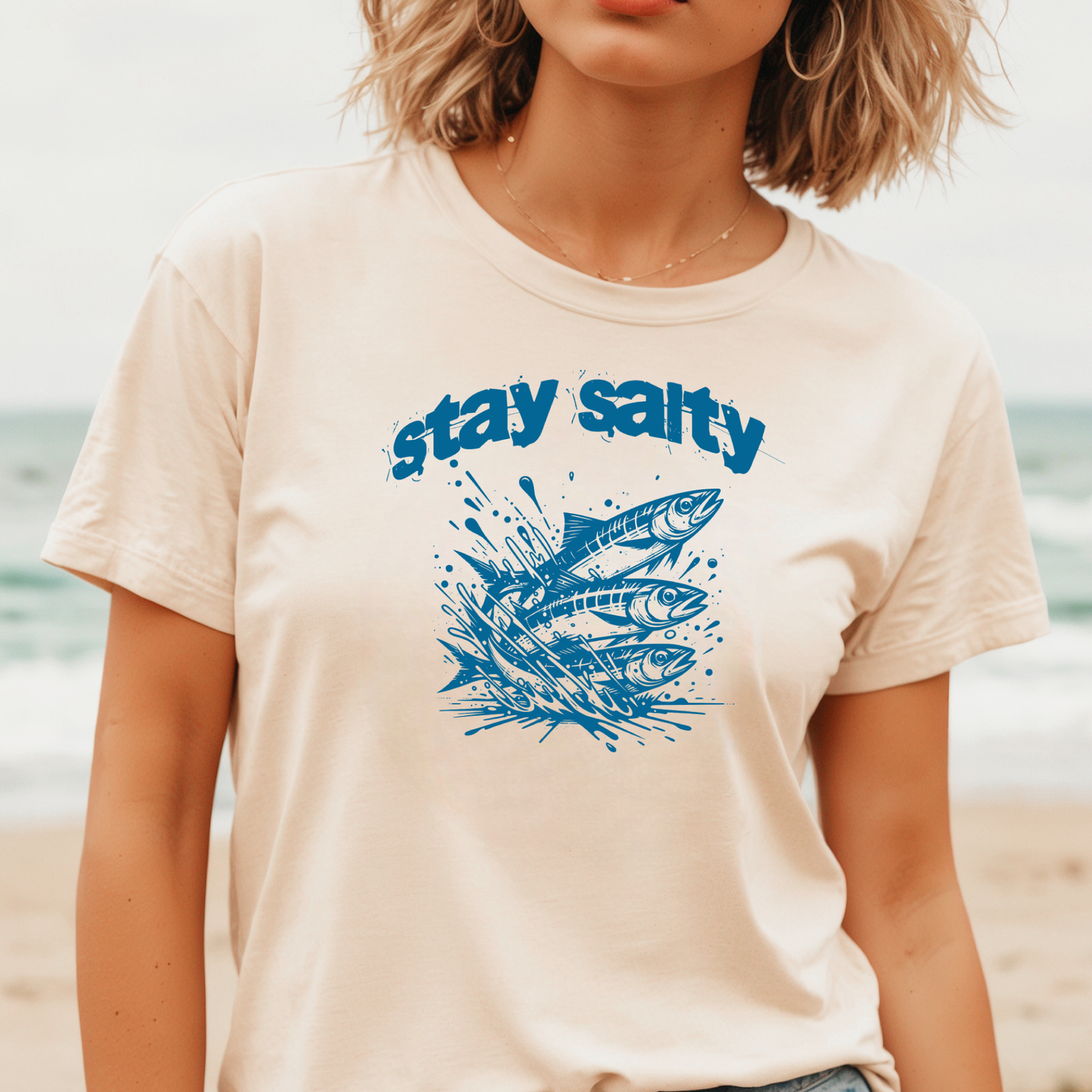 Gildan 5000 "Stay Salty" t shirt with Three Sardines jumping out of water in one color graphics. Picture of a girl standing on the beach wearing a t shirt.