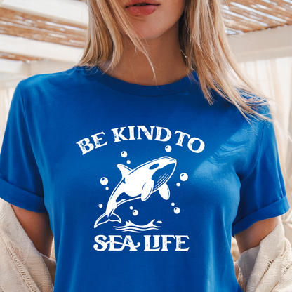 Person wearing a blue t-shirt with a whale graphic and text 'Be Kind to Sea Life'.