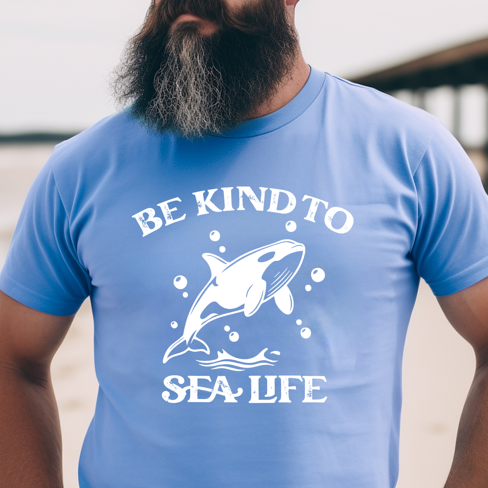Person wearing a Carolina blue t-shirt with a whale graphic and text 'Be Kind to Sea Life'.