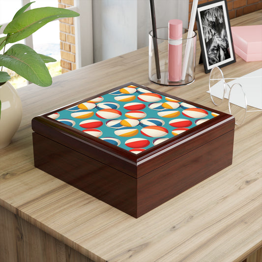 The Colorful Beach Ball Jewelry Box, crafted from rubberwood with a geometric pattern, graces a wooden table. Nearby are a plant, pen holder, eyeglasses, and framed photo, all enhancing the workspaces charm with its felt interior and brick wall backdrop.