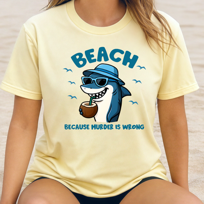 Person wearing a yellow t-shirt with a shark graphic and text on a beach.