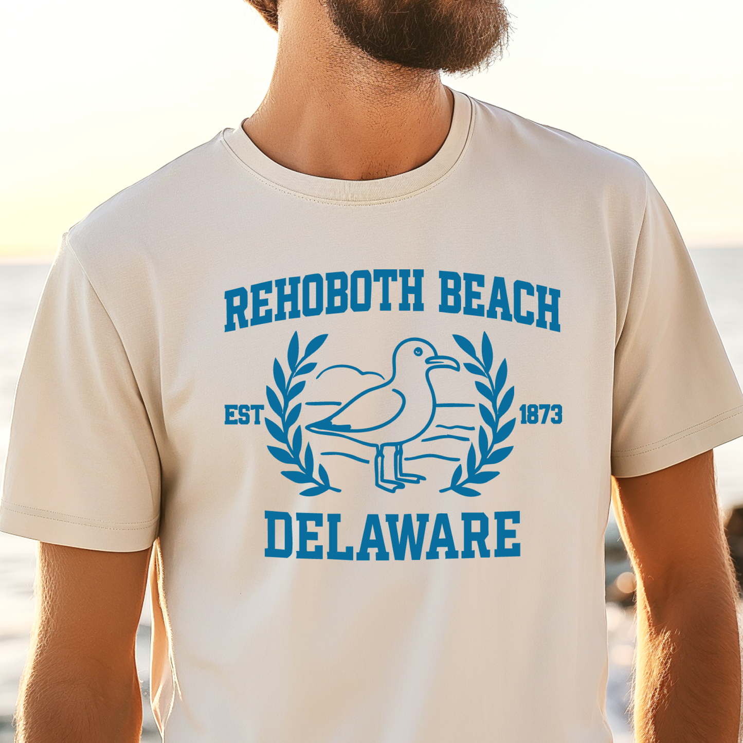 Person wearing a t-shirt with Rehoboth Beach, Delaware design on a beach.