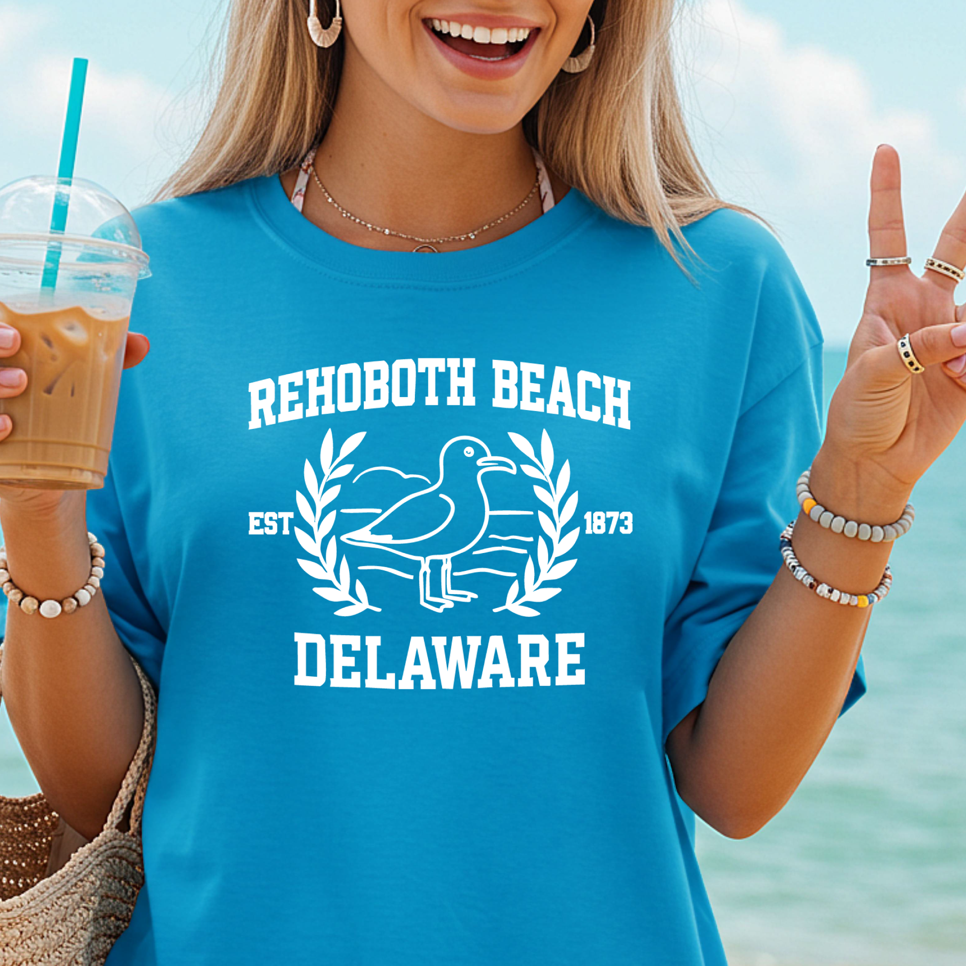 Woman wearing a blue 'Rehoboth Beach, Delaware' t-shirt by the beach.