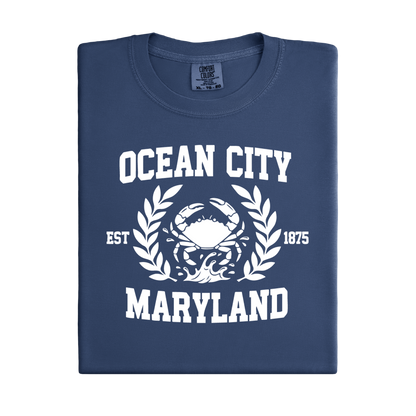 Folded navy blue t-shirt with white 'Ocean City, Maryland' text and crab graphic on a white background