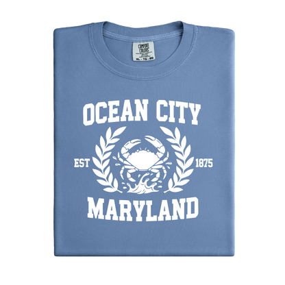 Folded blue t-shirt with 'Ocean City, Maryland' text and crab graphic on a white background
