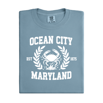 Folded ice blue t-shirt with 'Ocean City, Maryland' text and crab graphic on a white background