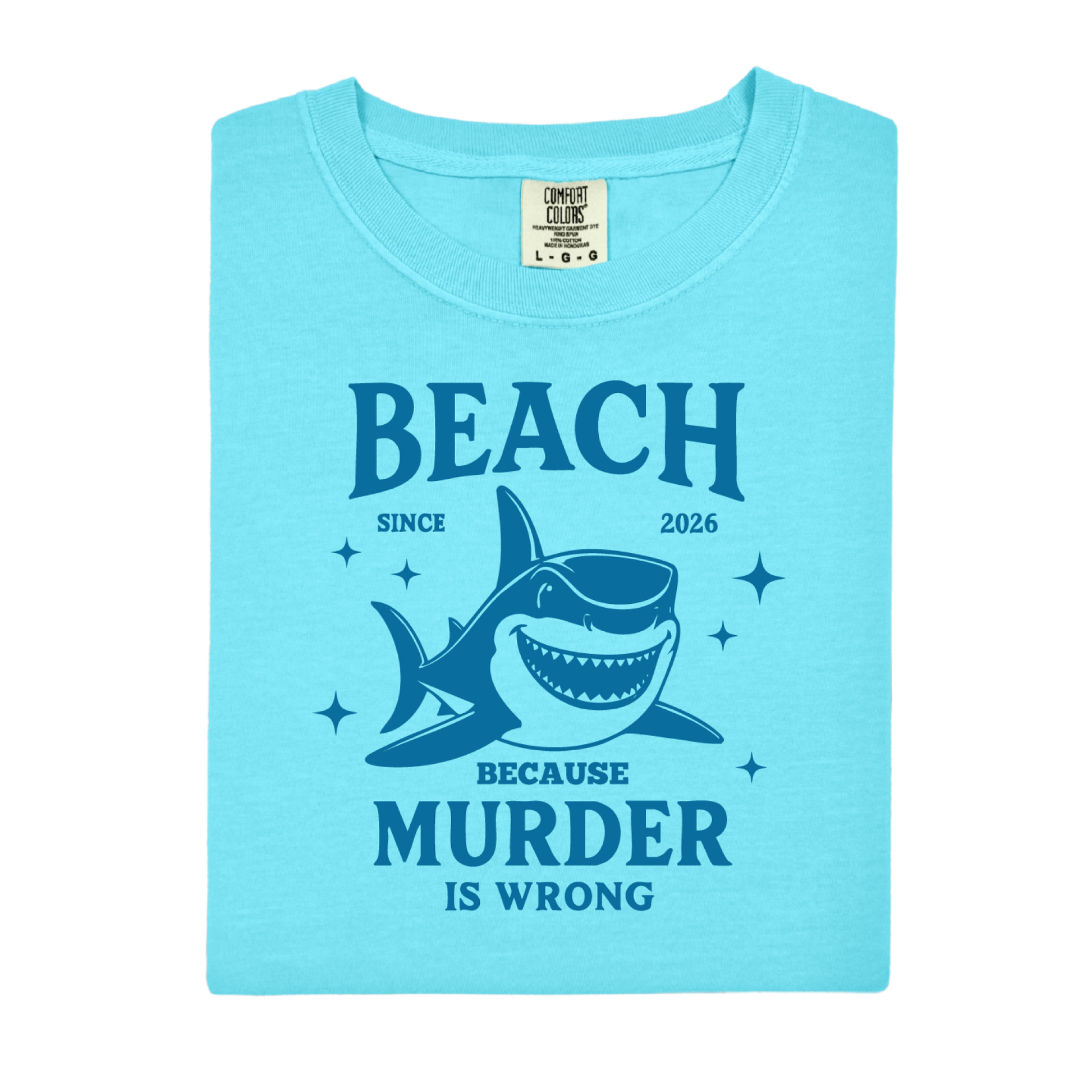 Comfort Colors t-shirt featuring a blue cartoon shark illustration with the humorous text “Beach Because Murder Is Wrong” and “Since 2026.” The design includes sparkling star accents for a fun coastal look. This unisex garment-dyed tee offers soft, vintage-style cotton and a relaxed fit, perfect for beach lovers, humor fans, and anyone who enjoys playful ocean-themed graphic shirts.