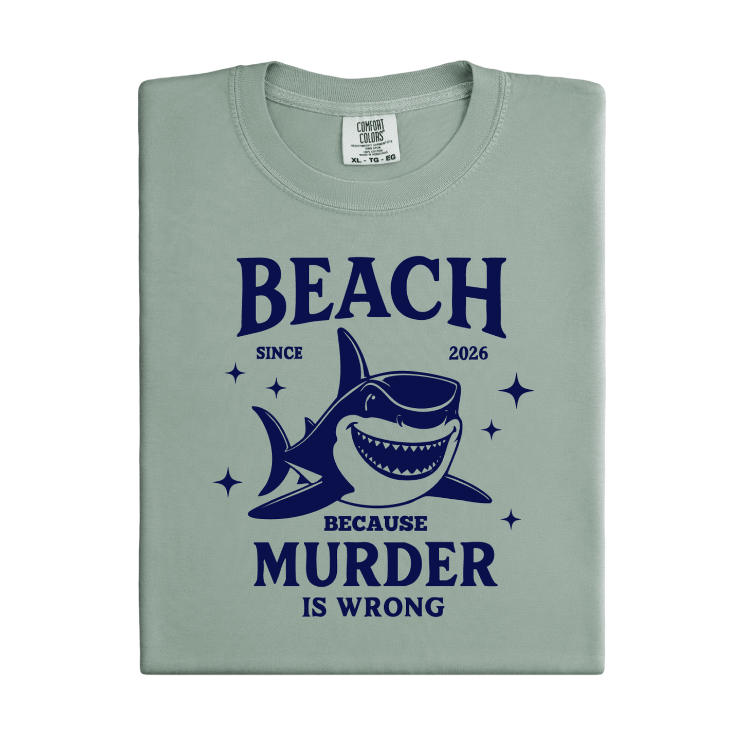 Comfort Colors t-shirt featuring a blue cartoon shark illustration with the humorous text “Beach Because Murder Is Wrong” and “Since 2026.” The design includes sparkling star accents for a fun coastal look. This unisex garment-dyed tee offers soft, vintage-style cotton and a relaxed fit, perfect for beach lovers, humor fans, and anyone who enjoys playful ocean-themed graphic shirts.