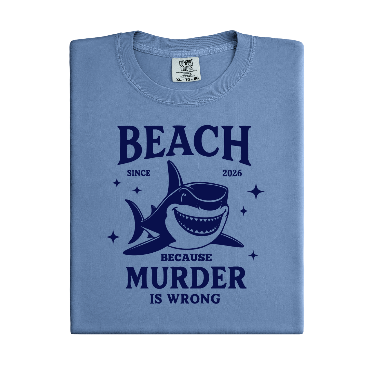 Comfort Colors t-shirt featuring a blue cartoon shark illustration with the humorous text “Beach Because Murder Is Wrong” and “Since 2026.” The design includes sparkling star accents for a fun coastal look. This unisex garment-dyed tee offers soft, vintage-style cotton and a relaxed fit, perfect for beach lovers, humor fans, and anyone who enjoys playful ocean-themed graphic shirts.
