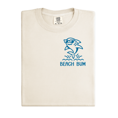 Beige t-shirt with blue shark graphic and 'Beach Bum' text on a white background