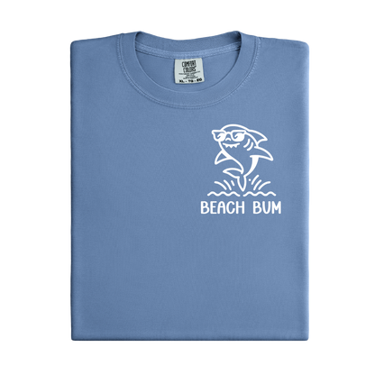 Folded blue t-shirt with a shark graphic and 'Beach Bum' text on a white background