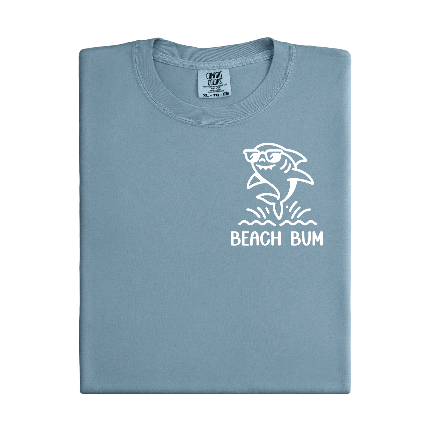Folded light blue t-shirt with a shark graphic and 'Beach Bum' text on a white background