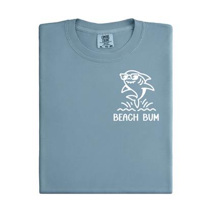 Folded light blue t-shirt with a shark graphic and 'Beach Bum' text on a white background
