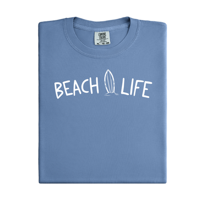 Folded blue jean t-shirt with 'Beach Life' text and surfboard graphic on a white background
