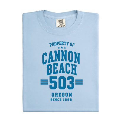 a t-shirt with 'Property of Cannon Beach 503 Oregon Since 1899' text at the beach.