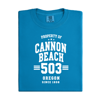 Blue t-shirt with white text 'Property of Cannon Beach 503 Oregon Since 1899' on a white background