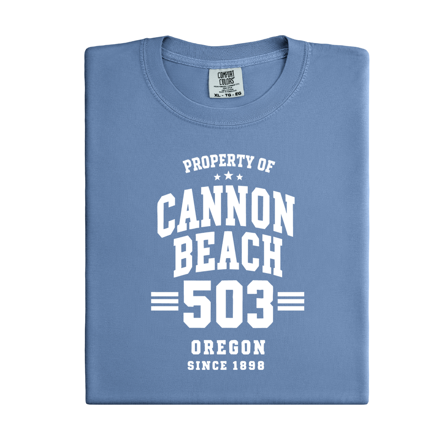 Folded blue t-shirt with 'Property of Cannon Beach 503 Oregon Since 1898' text on a white background