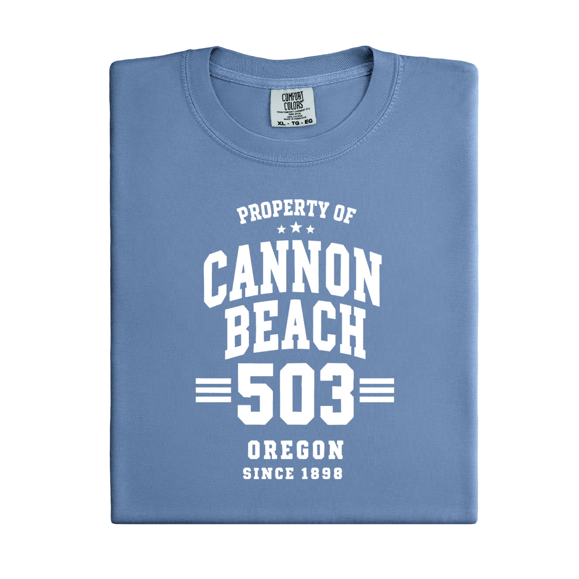 Folded blue t-shirt with 'Property of Cannon Beach 503 Oregon Since 1898' text on a white background