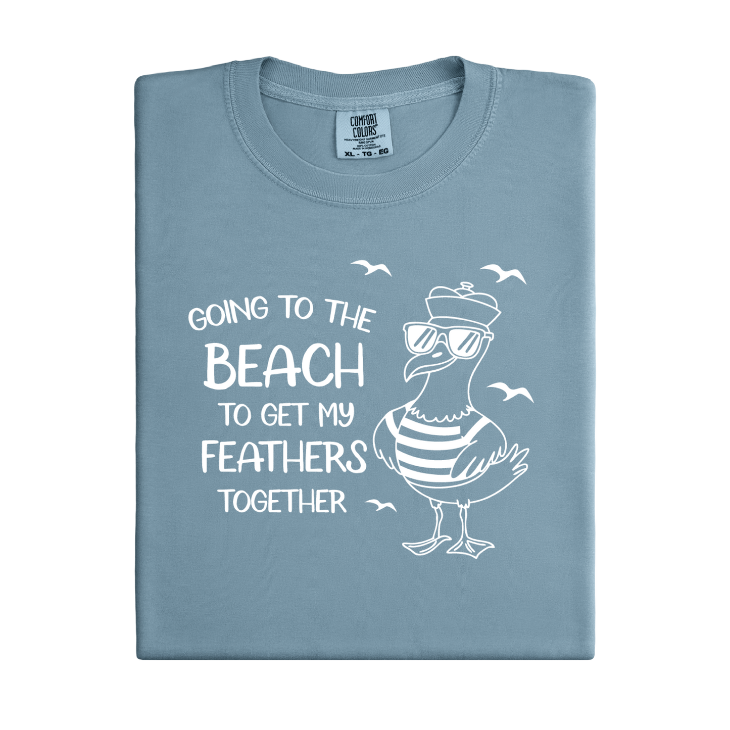 Comfort Colors t-shirt featuring a humorous blue seagull graphic wearing sunglasses and a striped shirt, beside the text “Going to the Beach to Get My Feathers Together.” Several flying birds surround the design, adding a fun coastal feel. This unisex garment-dyed tee offers a soft, vintage texture and relaxed fit, perfect for beach lovers, ocean fans, and anyone who enjoys playful summer graphic shirts.