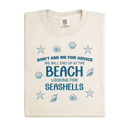 Beige t-shirt with blue text and shell graphics on a white background