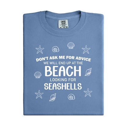 Folded blue t-shirt with beach-themed text and graphics on a white background