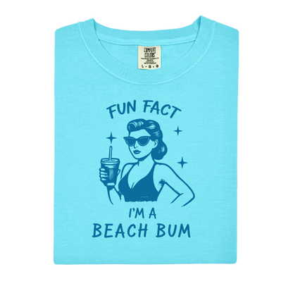 Light blue t-shirt with a graphic of a woman at the beach and text 'Fun Fact I'm a Beach Bum' on a white background.
