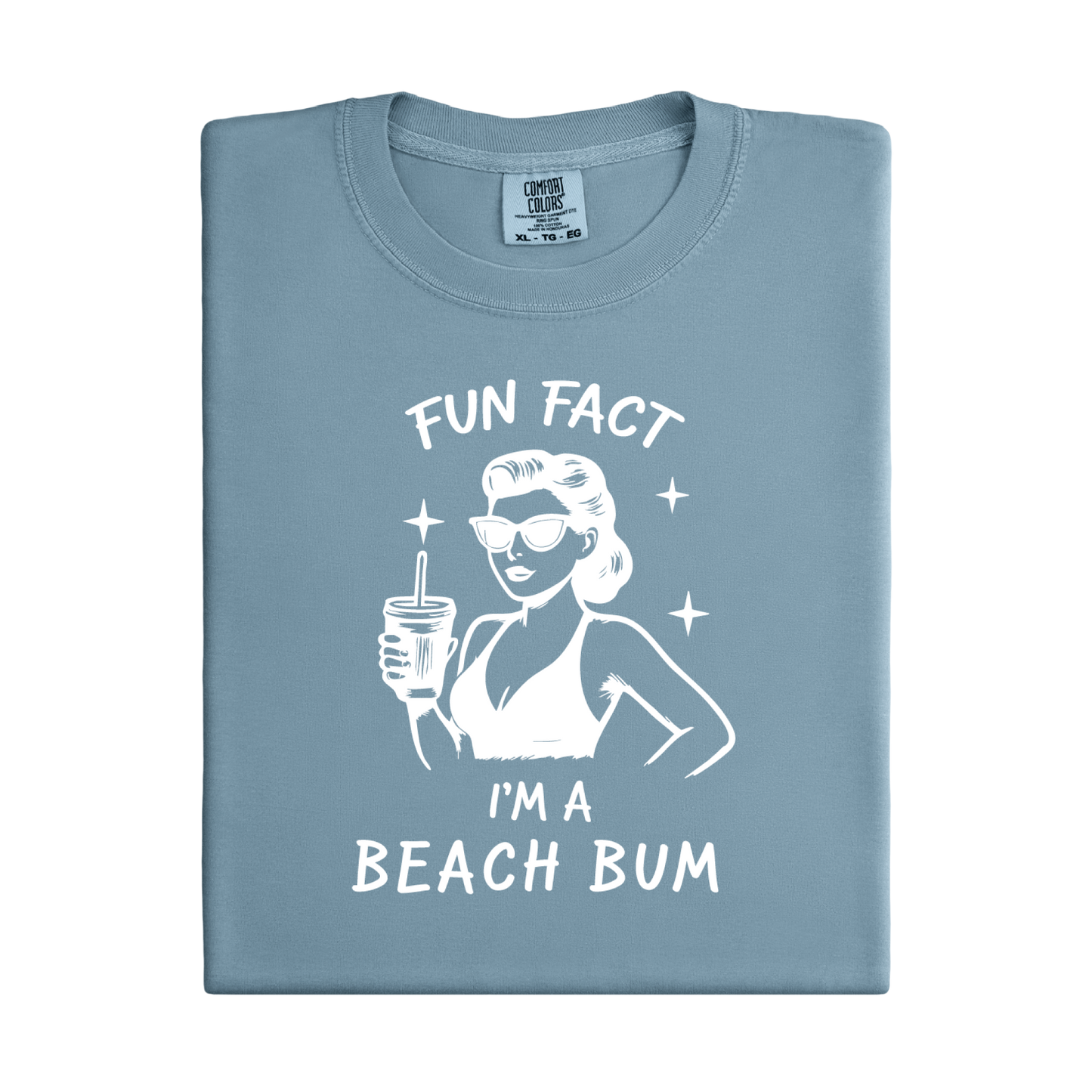Folded blue t-shirt with a graphic of a woman in a bikini holding a drink and text 'Fun Fact I'm a Beach Bum' on a white background.