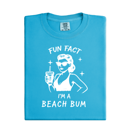 Blue t-shirt with a graphic of a woman at the beach and text 'Fun Fact I'm a Beach Bum' on a white background.