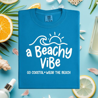 Blue t-shirt with 'a Beachy Vibe' text on a beach-themed background with lemons, oranges, and shells.