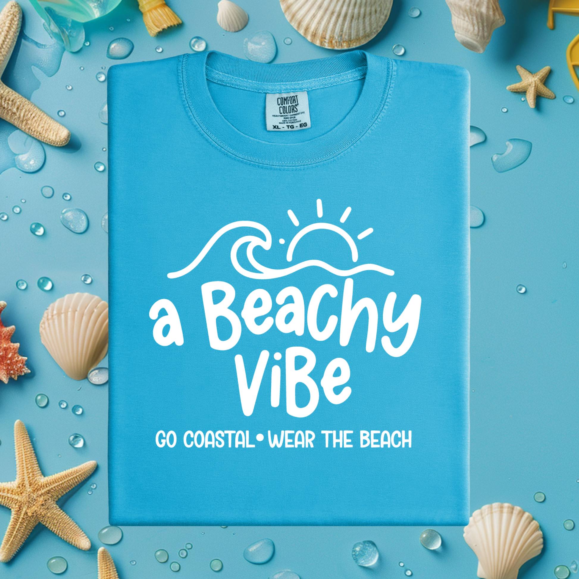 Blue t-shirt with 'a Beachy Vibe' text on a blue background with beach-themed decorations.