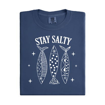 Folded navy blue t-shirt with 'Stay Salty' text and fish illustrations on a white background