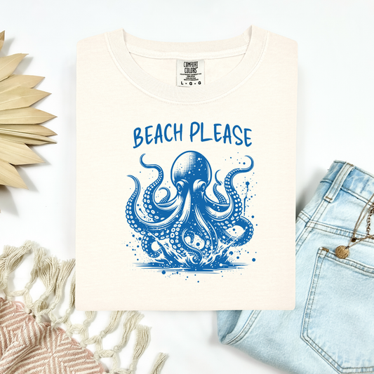 Comfort Colors 1717 "Beach Please" t shirt with a octopus  jumping in water in one color graphic. Picture on a flay lay mockup with pair of blue jeans and blanket and a wicker sun shaped accessory.
