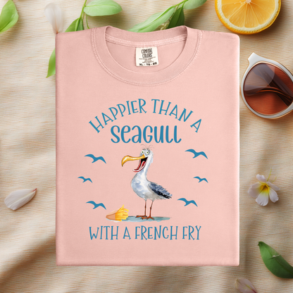Pink t-shirt with a seagull graphic and text on a wooden surface with lemon and flowers.