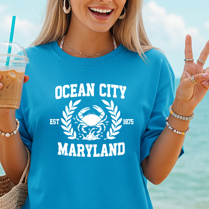 Person wearing a blue 'Ocean City, Maryland' t-shirt with a crab graphic by the ocean.