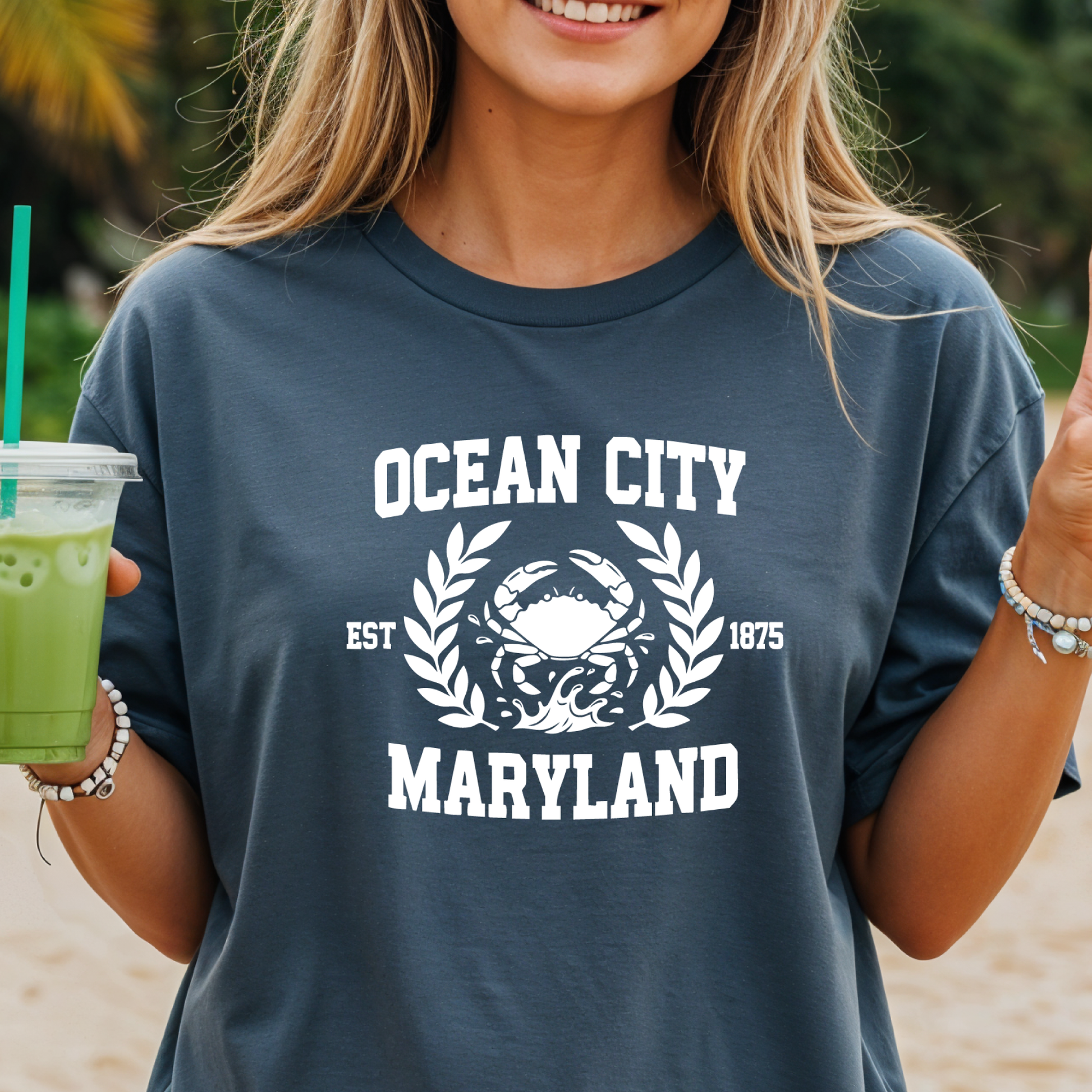 Person wearing a 'Ocean City, Maryland' t-shirt holding a green drink.
