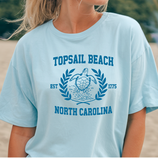 Light blue t-shirt with 'Topsail Beach, North Carolina' design on a blurred beach background