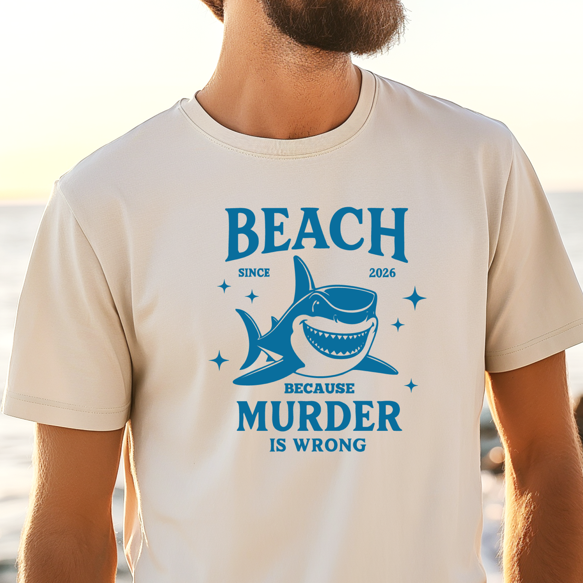 Comfort Colors t-shirt featuring a blue cartoon shark illustration with the humorous text “Beach Because Murder Is Wrong” and “Since 2026.” The design includes sparkling star accents for a fun coastal look. This unisex garment-dyed tee offers soft, vintage-style cotton and a relaxed fit, perfect for beach lovers, humor fans, and anyone who enjoys playful ocean-themed graphic shirts.