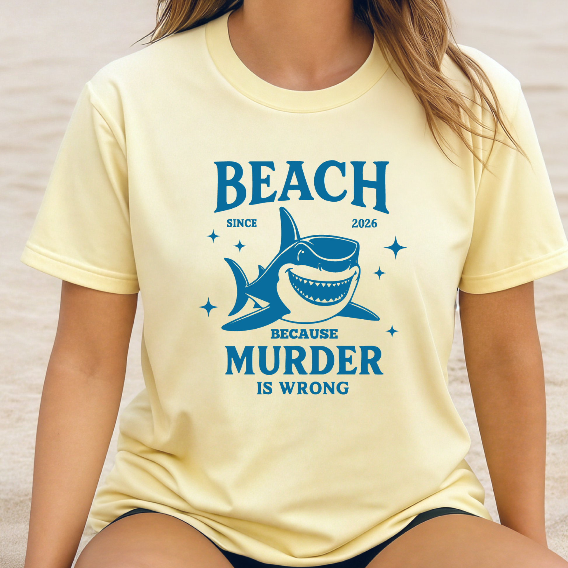 Comfort Colors t-shirt featuring a blue cartoon shark illustration with the humorous text “Beach Because Murder Is Wrong” and “Since 2026.” The design includes sparkling star accents for a fun coastal look. This unisex garment-dyed tee offers soft, vintage-style cotton and a relaxed fit, perfect for beach lovers, humor fans, and anyone who enjoys playful ocean-themed graphic shirts.
