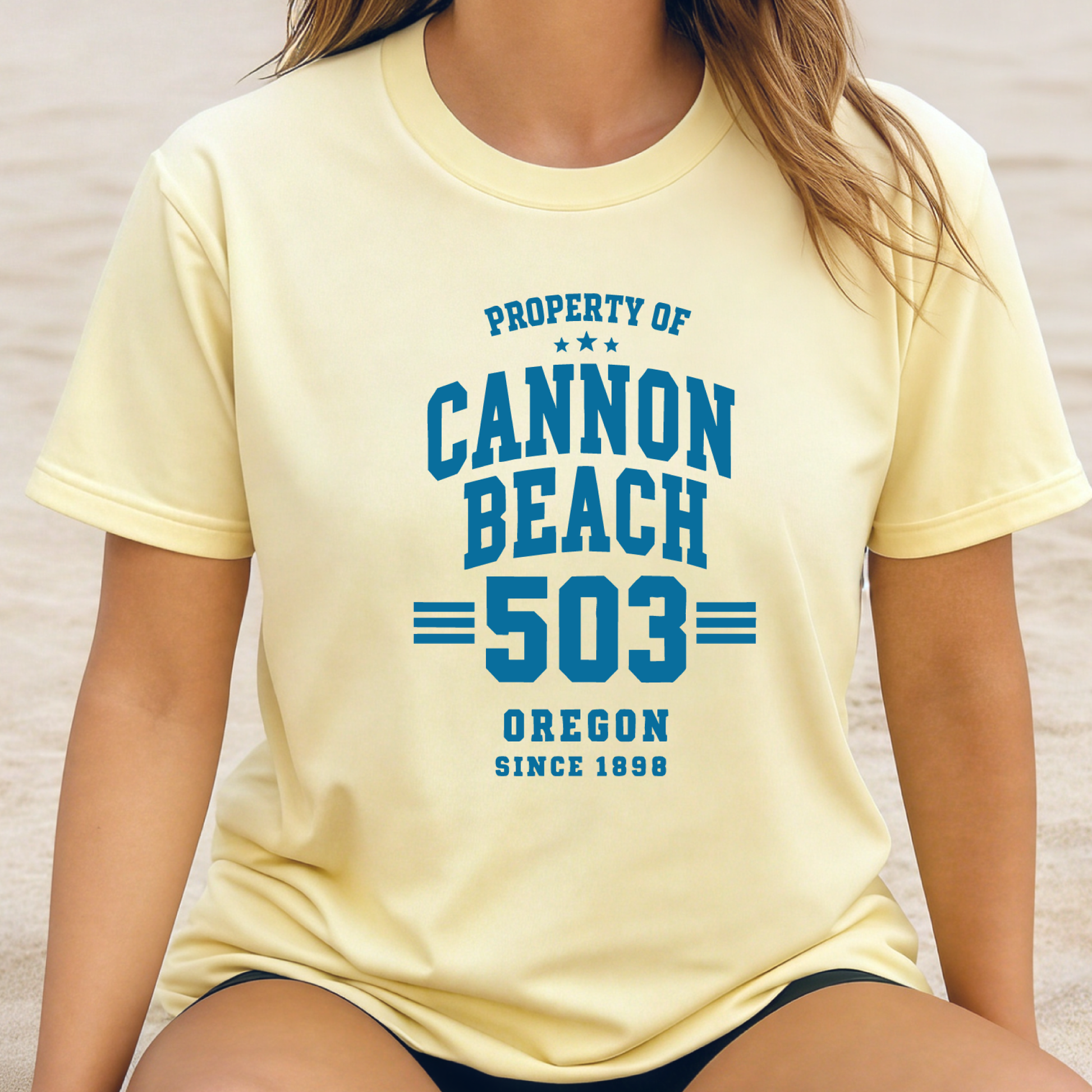Person wearing a yellow t-shirt with 'Property of Cannon Beach 503 Oregon Since 1896' text.