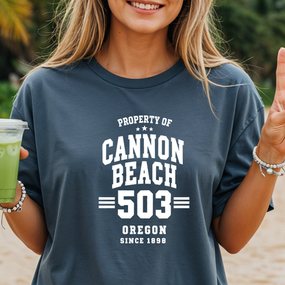 Person wearing a t-shirt with 'Property of Cannon Beach 503 Oregon Since 1896' on a beach.